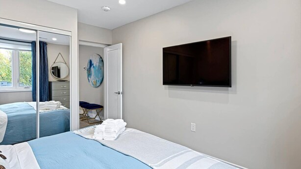 Un dormitorio con dos camas, un televisor montado en la pared y una puerta que da a un baño.