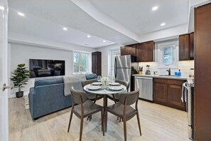 Una cocina moderna con armarios de madera oscura, un refrigerador de acero inoxidable y un comedor con una mesa redonda y sillas.