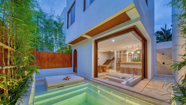 A modern house with a glass-enclosed patio, a pool, and a staircase leading to the interior. - Villa Gloria Canggu (Canggu)