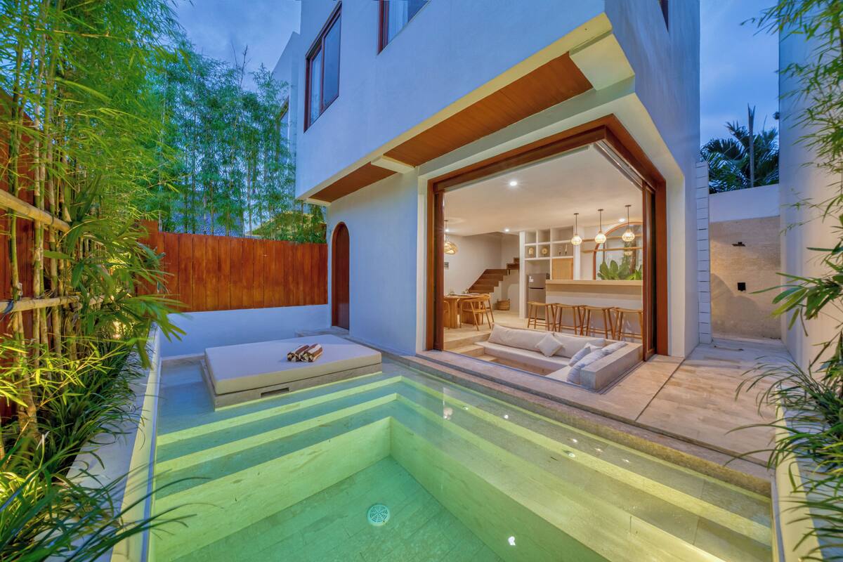 A modern house with a glass-enclosed patio, a pool, and a staircase leading to the interior.