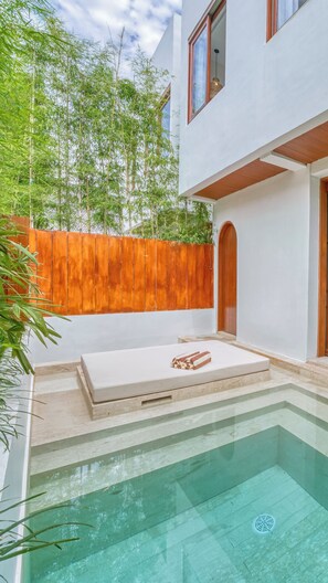 A modern house with a swimming pool, wooden fence, and a bench with towels.
