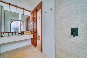 A modern bathroom with a large mirror, wooden door, and a towel rack. - Villa Gloria Canggu (Canggu)
