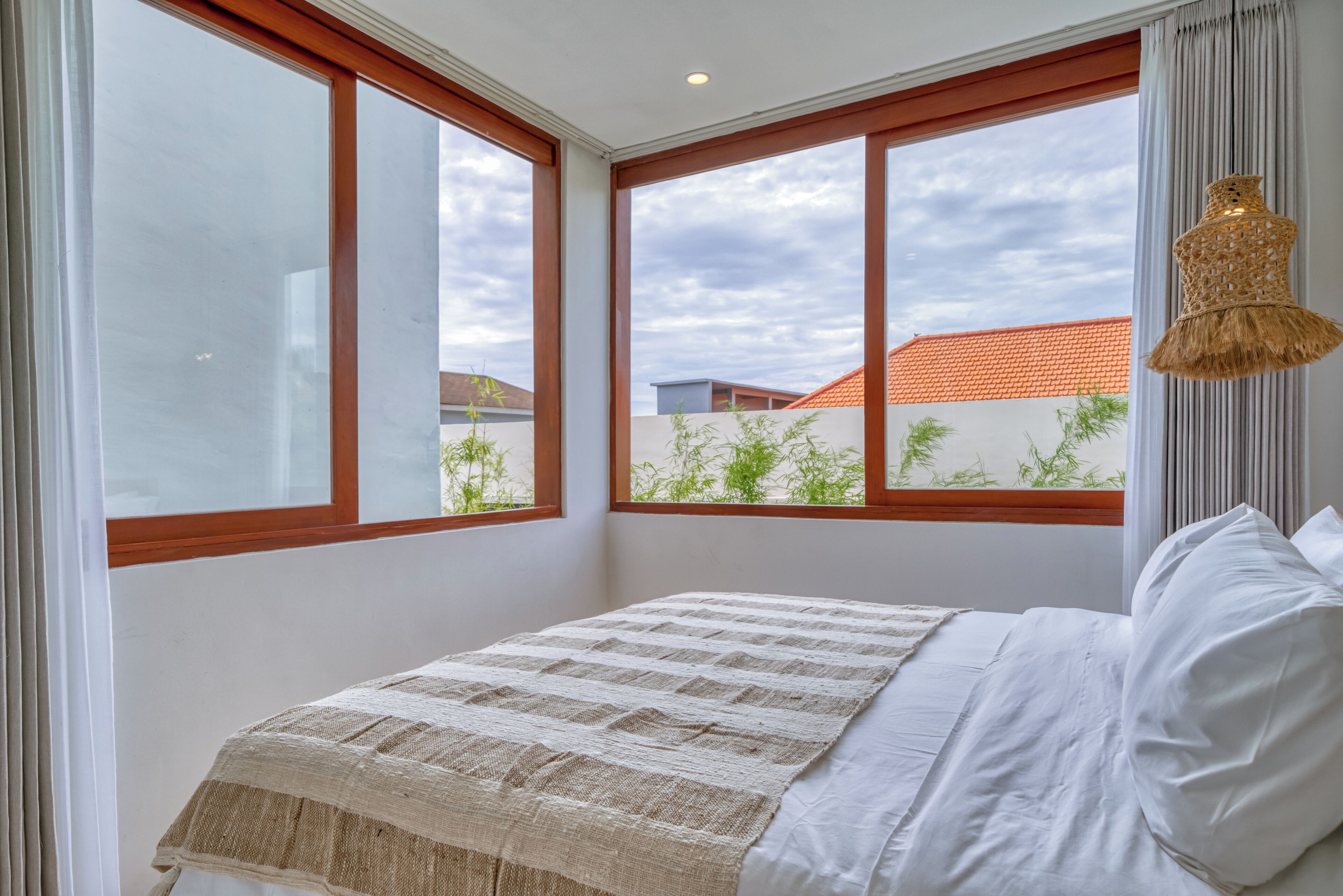 Una camera da letto con un letto, ampie finestre e una lampada a sospensione.