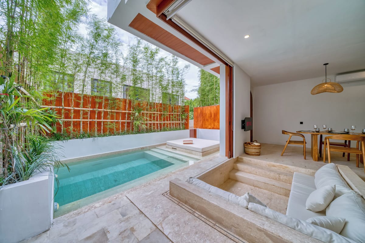 A modern outdoor living area with a pool, steps leading to a seating area, and a dining setup.