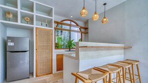 A modern kitchen with a built-in refrigerator, wooden stools, and a large window overlooking greenery. - Villa Gloria Canggu (Canggu)
