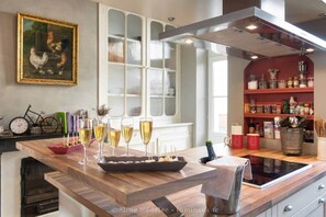 A modern kitchen with a wooden island, wine glasses, and a painting on the wall.