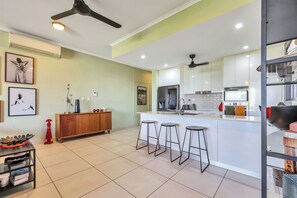 Uma cozinha moderna com ilha central, banquetas e ventilador de teto.