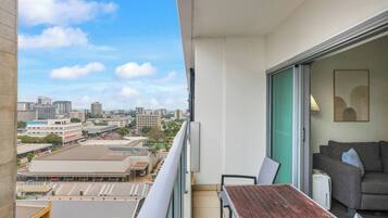 Ein Balkon mit Blick auf die Stadt, ein graues Sofa und ein Holztisch.