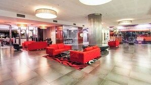 A spacious lobby with red seating, a large pillar, and a modern ceiling design.