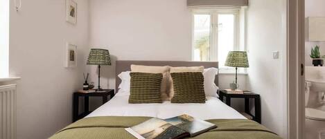 A bedroom with a bed, two bedside tables, two lamps, a window, and a magazine on the bed.