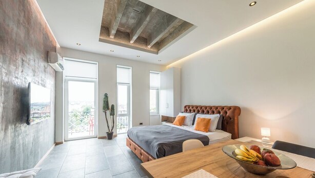 Een moderne slaapkamer met een groot bed, een houten eettafel en uitzicht over de stad.