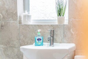 A bathroom sink with a bottle of Carex hand soap and a modern faucet.
