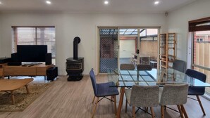 Un salon moderne avec une table à manger en verre, des sièges confortables, un téléviseur et un poêle à bois.