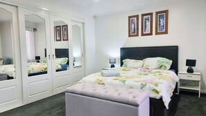 Une chambre à coucher comprenant un lit, une table de chevet, une lampe, un banc et une armoire avec des miroirs.