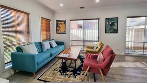 Un salon moderne avec un canapé bleu, un fauteuil rouge, une table basse en bois et un tapis à motifs.