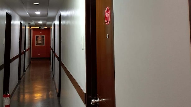 A hotel hallway with doors, a fire extinguisher, and a red exit sign. - WJV Mia Hotel Humay-Humay (Lapu-Lapu)