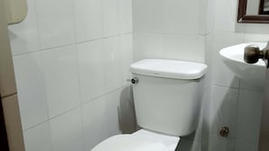 A small, white-tiled bathroom with a white toilet and a sink. - WJV Mia Hotel Humay-Humay (Lapu-Lapu)