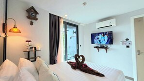 A hotel room with a bed, a wall clock, a television, and a window with curtains. - A204 - 1 Bdr Condo With Sea View, Ao Nang Beach (Krabi)