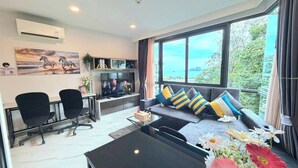 A modern living room with a sofa, two chairs, a TV, and a large window with a view. - A204 - 1 Bdr Condo With Sea View, Ao Nang Beach (Krabi)