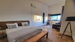 Une chambre à coucher moderne avec un grand lit, un banc en bois, un bureau et une lampe sur pied.