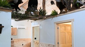 A room with wooden floors, a ceiling with wooden beams, and a bear and owl mounted on the wall. - Riverfront Bear Cabin (Paris)