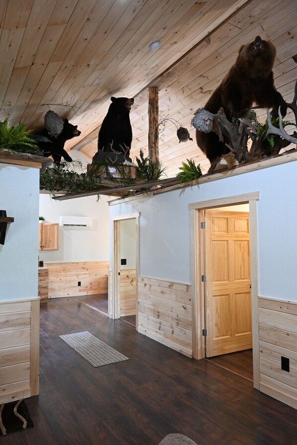 A room with wooden floors, a ceiling with wooden beams, and a bear and owl mounted on the wall.