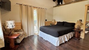 A bedroom with a bed, a ceiling fan, a mounted TV, and a bear decoration on the wall. - Riverfront Bear Cabin (Paris)