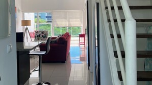 Un interior moderno con una escalera, un sofá rojo y un comedor con una lámpara.