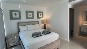 Un dormitorio ordenado con cama, mesitas de noche, lámpara y decoración en la pared.