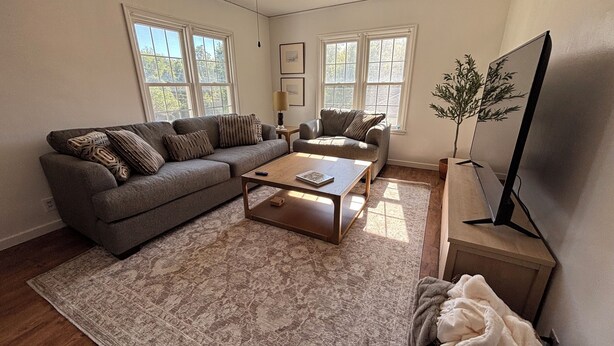 Una sala de estar con sofá, mesa de centro y mueble para televisión.