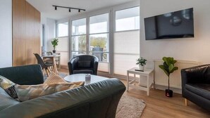 Una sala de estar moderna con un sofá, una mesa de centro y un televisor montado en la pared.