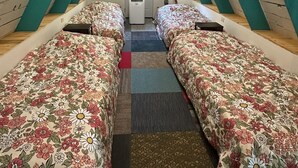A room with two beds, a door, and a ceiling fan.