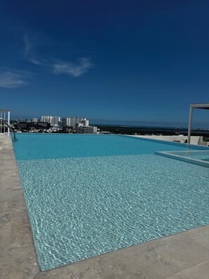 Une piscine d’un bleu éclatant, avec une vue sur la ville en arrière-plan.