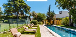 Une villa de luxe dotée d’une piscine, de chaises longues et d’un jardin bien entretenu.