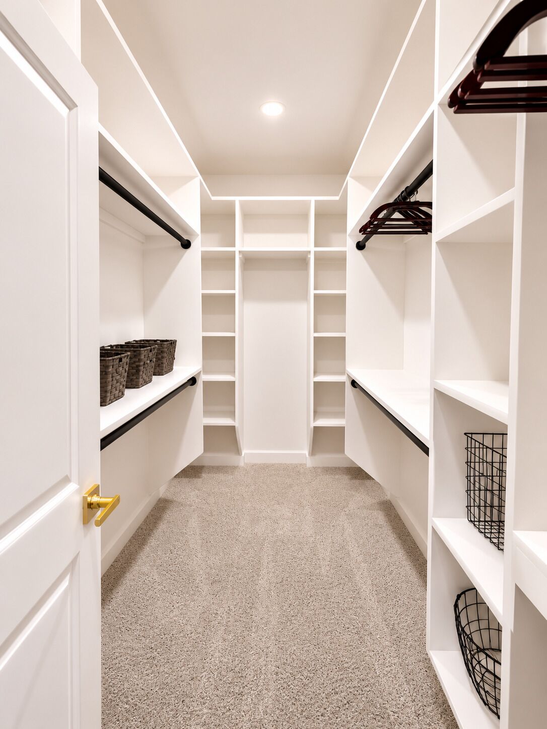 A walk-in closet with multiple shelves and hanging space, carpeted floor, and a visible door handle.