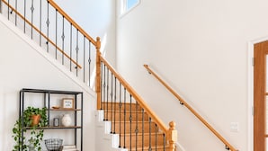 A staircase with wooden steps and black balusters, leading to a landing with a white wall and a small window.