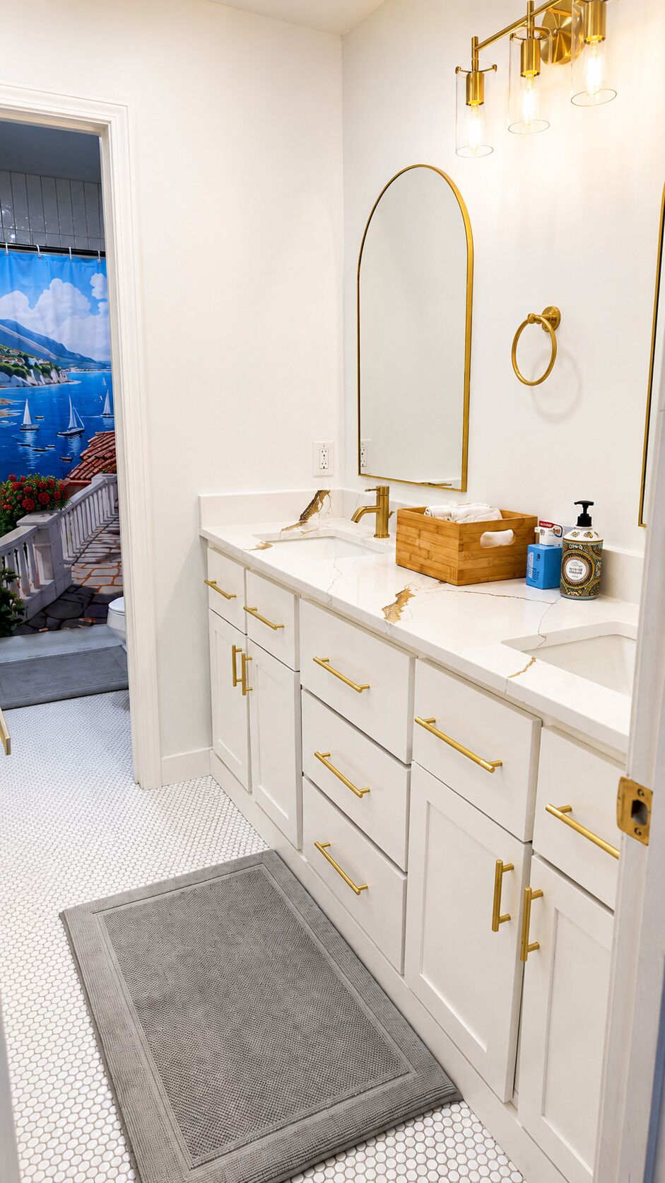 A bathroom with a white vanity, gold fixtures, and a large mirror.