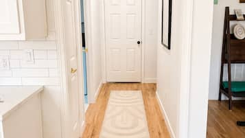 Un couloir avec un plancher en bois, des murs blancs et une porte blanche au fond.