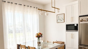 A modern kitchen with a dining table, chairs, and a refrigerator.