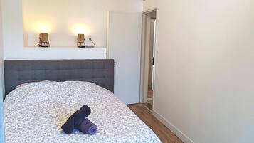 A bedroom with a bed, a headboard, a nightstand, and two wall-mounted lamps.