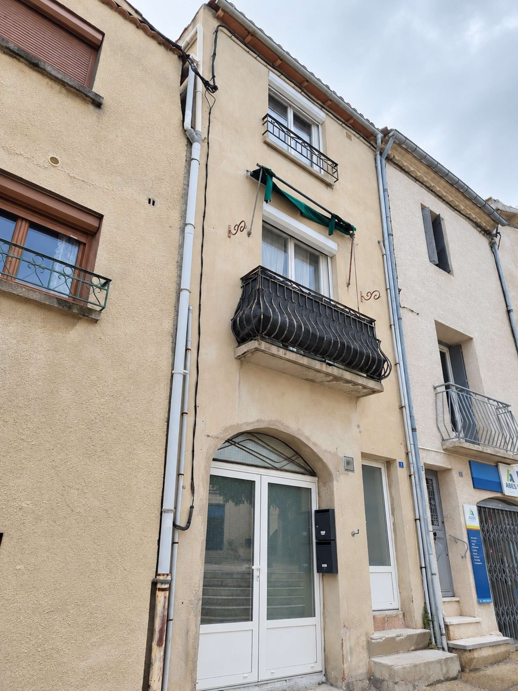 A building with a white door, a balcony with a metal railing, and a window with a curtain.