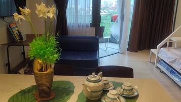 A hotel room with a dining table set with a teapot and cups, a sofa, and a bed.