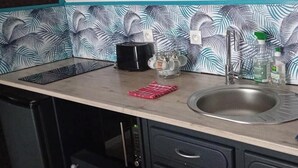 Una cocina con mostrador, lavamanos y cafetera.