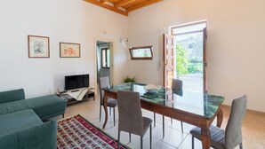 Una sala de estar con una mesa de comedor de vidrio, sofás grises y un televisor.