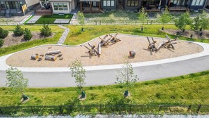 Zona residencial com casas modernas, um parque ajardinado com área de recreação circular e uma rua.