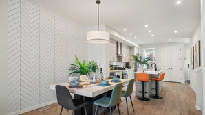 Uma cozinha moderna com armários brancos, uma ilha central e banquetas laranjas.