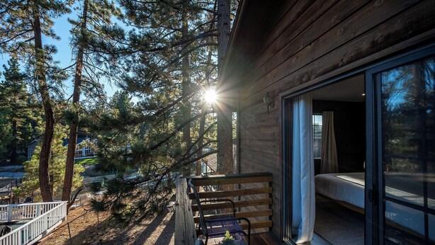 Une cabane en bois dotée d’un balcon, d’un lit et d’une table avec des tasses et une plante.