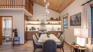 Une cuisine moderne dotée d’un îlot central, d’un plafond en bois et de luminaires suspendus.