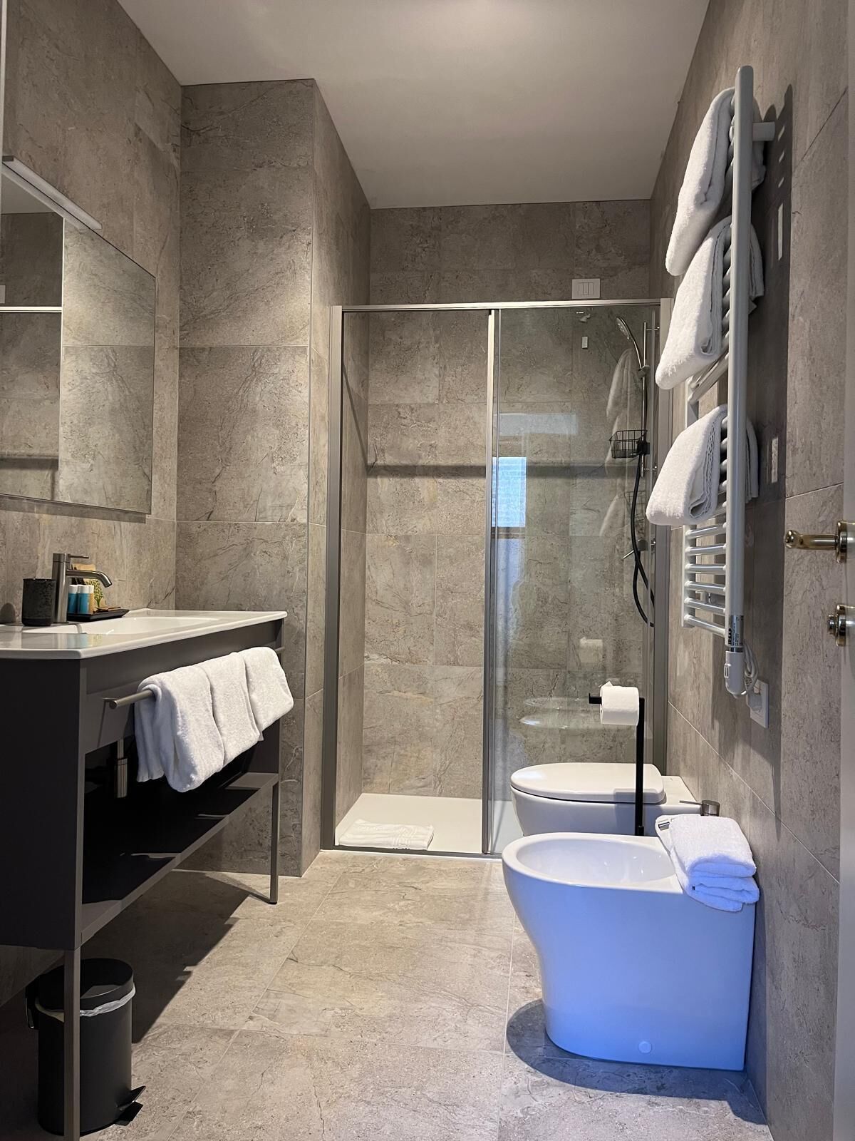 A modern bathroom with a glass-enclosed shower, a freestanding bathtub, and a vanity with a towel rack.