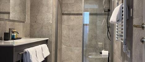 A modern bathroom with a glass-enclosed shower, a freestanding bathtub, and a vanity with a towel rack.
